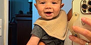 Hudson joined the competition — help win amazing prizes! adult_hand, baby, bib, child, door, face, furniture, hair, happy, head, holding, indoor, mirror_selfie, person, photography, room, short_sleeve, skin, smartphone, smiling