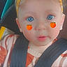 Olivia is registered to the contest to win money with this photo: toddler, child, car_seat, headband, yellow_bow, blue_eyes, freckles, peach_emoji, face, close_up, straps, safety, cute, expression, infant, baby_clothes, orange_and_white, indoors, portrait, person