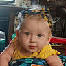 baby, child, infant, yellow_clothing, headband, face, eyes, indoor, furniture, toy, curious, closeup, person, portrait, colorful, candid, cute, soft_focus, young_child, home