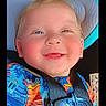 baby, child, car_seat, smiling, blue_eyes, colorful_clothing, safety_harness, happy, closeup, infant, cute, portrait, seat_belt, car_accessory, baby_face, young_child, cute_expression, indoor, bright_colors, child_in_car_seat