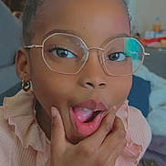 Jhaëlys a rejoint le concours — aidez-le/la à gagner de superbes lots ! child, girl, glasses, surprised, hand, pink_clothing, curly_hair, indoor, portrait, face, expression, earring, casual, young, person, fashion, home, closeup, smile, cute