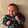 baby, smiling, happy, infant, blue_clothing, floral_pattern, blanket, texture, cheeks, fist, cute, lying_down, portrait, child, young, face, skin, head, small_hands, cozy