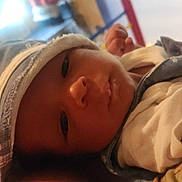 Cameron is registered to the contest to win money with this photo: baby, blanket, child, closeup, clothing, cozy, cute, face, hat, headwear, indoors, infant, newborn, person, portrait, resting, sleepy, soft_light, warm_colors, young
