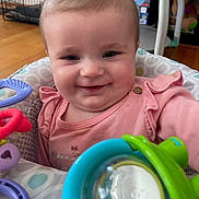 Kinslee is registered to the contest to win money with this photo: baby, child, closeup, colorful, cute, face, furniture, happy, home, human, indoor, infant, person, pink_clothing, playtime, portrait, seat, smiling, toy, wooden_floor