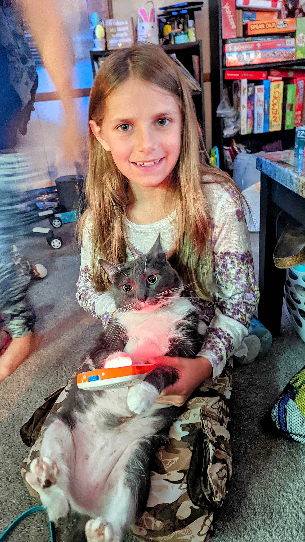 Tay is registered to the contest to win money with this photo: blond, bookcase, carnivore, cat, child, companion_dog, fawn, felidae, hairstyle, joy, lap, long_hair, mammal, person, publication, shelf, small_to_medium_sized_cats, smile, tail, toy