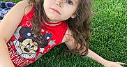 Elena is registered to the contest to win money with this photo: blanket, bottle, brown_eyes, brown_hair, child, daylight, disney, girl, grass, lawn, long_hair, lying_down, minnie_mouse, outdoor, picnic, playful, portrait, red_shirt, smiling, toddler