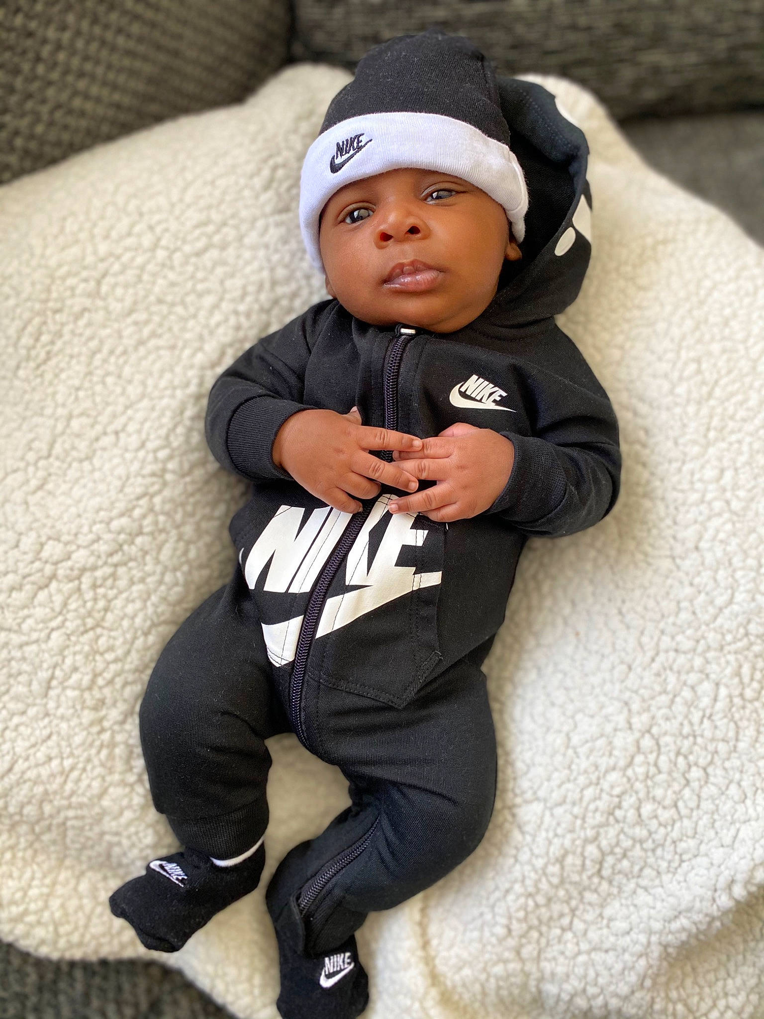 Mekhai is registered to the contest to win money with this photo: arm, baby, baby_products, baby_toddler_clothing, cap, carmine, child, comfort, couch, eye, face, flash_photography, headwear, knee, person, personal_protective_equipment, sitting, sleeve, sock, thigh