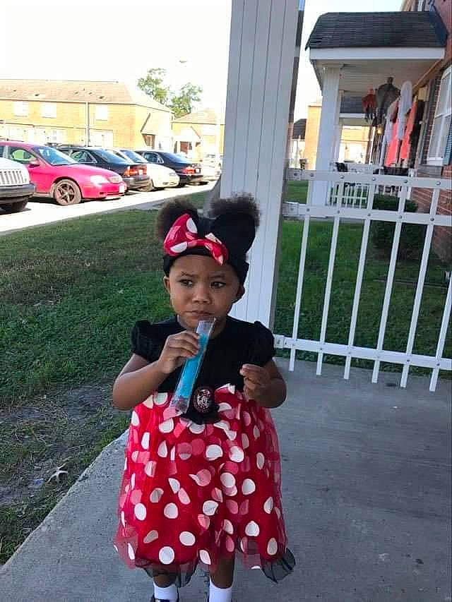 Skylar is registered to the contest to win money with this photo: asphalt, cap, car, costume, family_car, fence, fun, hat, headwear, holiday, magenta, pattern, person, plant, recreation, sky, sleeve, street_fashion, tire, toddler