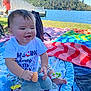 River is registered to the contest to win money with this photo: baby, child, smiling, toy, blanket, outdoor, lake, water, trees, nature, sunny, grass, colorful, clothing, foot, person, play, happy, scenic, relax