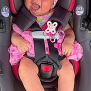 Kailani is registered to the contest to win money with this photo: baby, infant, car_seat, pink, headband, smiling, happy, tutu, dress, barefoot, safety_harness, child, cute, outdoor, grass, seat, person, baby_girl, joyful, closeup