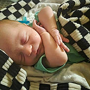 Brodie is registered to the contest to win money with this photo: baby, newborn, sleeping, blanket, black_and_white, checkered, arms, peaceful, cozy, infant, soft, wrapped, closeup, face, skin, child, rest, indoors, cute, quiet