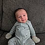 baby, infant, newborn, couch, onesie, mittens, face, head, smile, sitting, upholstery, texture, pattern, zipper, clothing, indoor, portrait, cozy, adorable, relaxed
