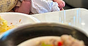 Oliver is registered to the contest to win money with this photo: baby, infant, thumb_sucking, cloth, cushion, yellow, face, eyes, indoor, table, food, blurred_background, person, seated, curious, skin, head, hand, expression, closeup