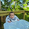 Oliver joined the competition — help win amazing prizes! baby, high_chair, outdoor, deck, wood, greenery, trees, nature, infant, curious, baby_bib, table, face, person, child, summer, daylight, cute, portrait, baby_clothing
