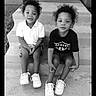 black_and_white, casual_clothing, children, concrete, curly_hair, front_door, front_porch, happy, monochrome, outdoor, pair, portrait, siblings, sitting, smiling, sneakers, steps, toddler, two_children, young_kids