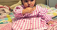 Juila is registered to the contest to win money with this photo: toddler, child, baby, bed, blanket, pink, dress, pigtails, hair_ties, indoor, furniture, mirror, cute, person, foot, hand, striped, plush, cozy, curious