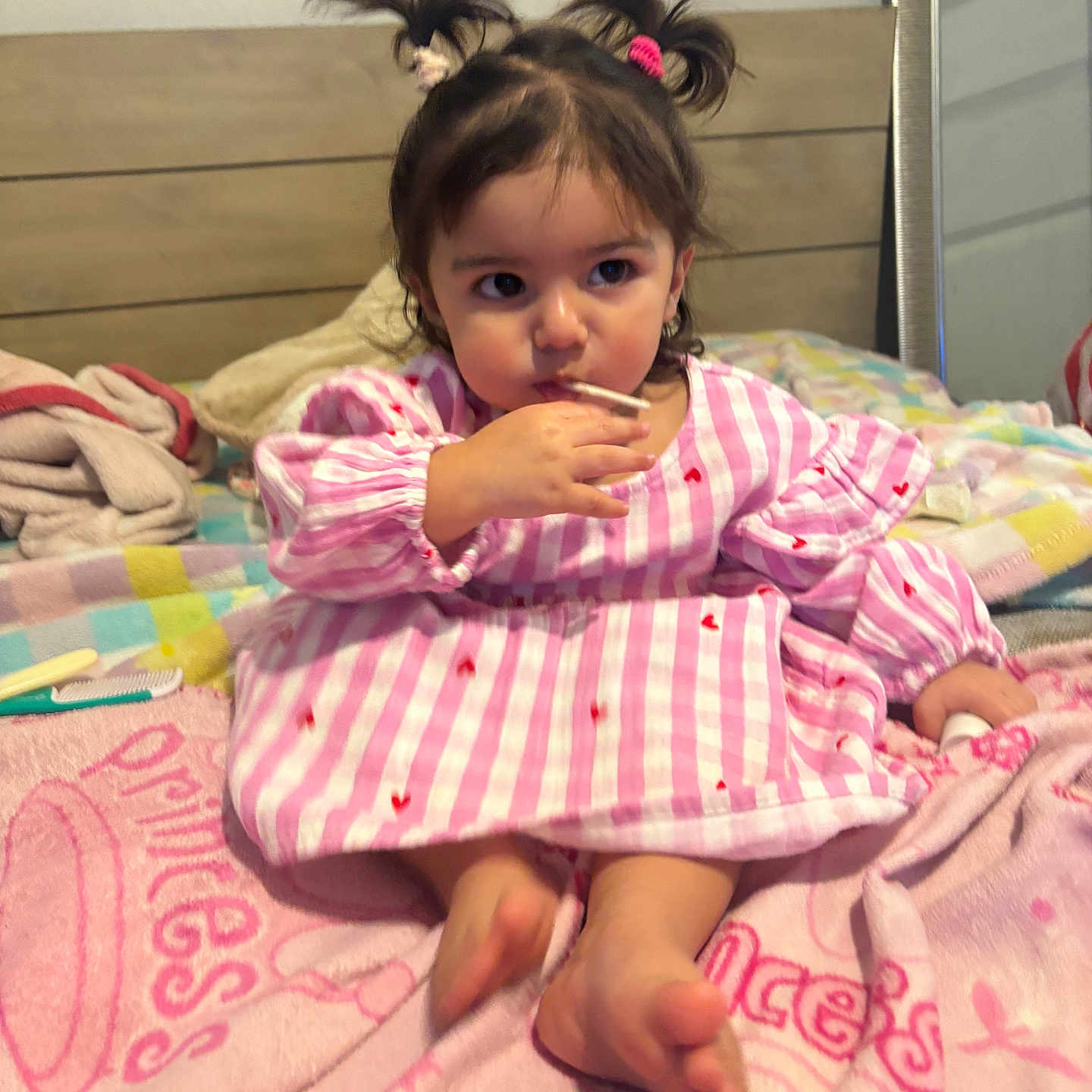 Juila is registered to the contest to win money with this photo: toddler, child, baby, bed, blanket, pink, dress, pigtails, hair_ties, indoor, furniture, mirror, cute, person, foot, hand, striped, plush, cozy, curious