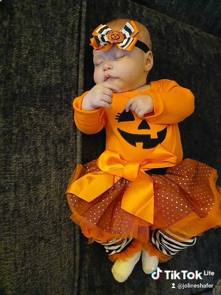 Jayla is registered to the contest to win money with this photo: baby, sleeping, orange_clothing, pumpkin_face, headband, bow, tutu_skirt, striped_leggings, footwear, infant, costume, cute, holiday, halloween, resting, soft_toys, indoor, portrait, child, cozy