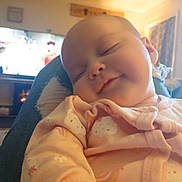 Jayla joined the competition — help win amazing prizes! baby, sleeping, pajamas, infant, person, smile, face, indoor, living_room, cozy, television, blurred_background, soft_lighting, comfort, child, cute, rest, relaxation, home, casual