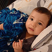 Ella is registered to the contest to win money with this photo: baby, child, blanket, blue, cushion, face, infant, indoors, laying_down, looking_at_camera, person, plush, soft, young, cute, expression, hand, head, comfort, resting