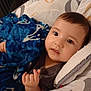 baby, child, blanket, blue, cushion, face, infant, indoors, laying_down, looking_at_camera, person, plush, soft, young, cute, expression, hand, head, comfort, resting