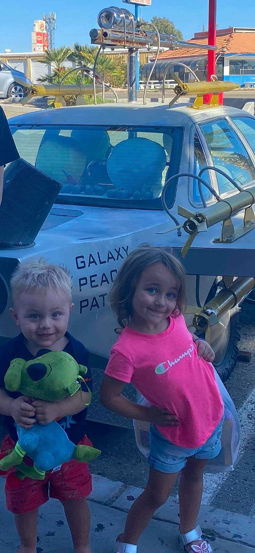 Kyra is registered to the contest to win money with this photo: automotive_design, automotive_exterior, blue, car, fun, happy, hood, joy, land_vehicle, leisure, motor_vehicle, person, photograph, pink, product, smile, snapshot, summer, toddler, trunk