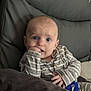 Jayden is registered to the contest to win money with this photo: baby, child, clothing, comfort, couch, curious, expression, eyes, face, fingers, hand, head, indoors, infant, leather, person, sitting, skin, striped, young