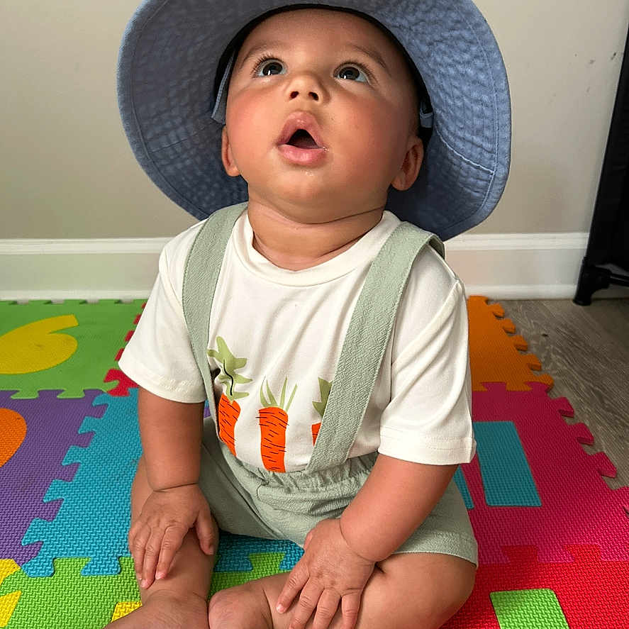 Coltan joined the competition — help win amazing prizes! baby, bodypart, bonnet, cap, clothing, face, finger, hand, happy, hat, head, mat, pants, person, photography, portrait, sitting, smile, sunhat, t_shirt
