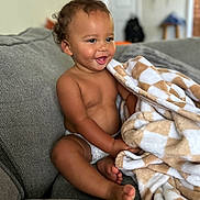 Coltan joined the competition — help win amazing prizes! baby, blanket, child, comfort, couch, cozy, curly_hair, diaper, expression, furniture, happy, home, indoor, person, playful, portrait, seated, skin, smiling, toddler