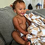 baby, blanket, child, comfort, couch, cozy, curly_hair, diaper, expression, furniture, happy, home, indoor, person, playful, portrait, seated, skin, smiling, toddler