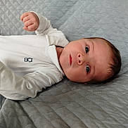 Gabin participe au concours pour gagner de l'argent avec cette photo : baby, infant, face, eyes, hand, onesie, white_clothing, blanket, quilted, soft_texture, lying_down, portrait, young_child, skin, head, curious, indoors, person, newborn, sleepwear