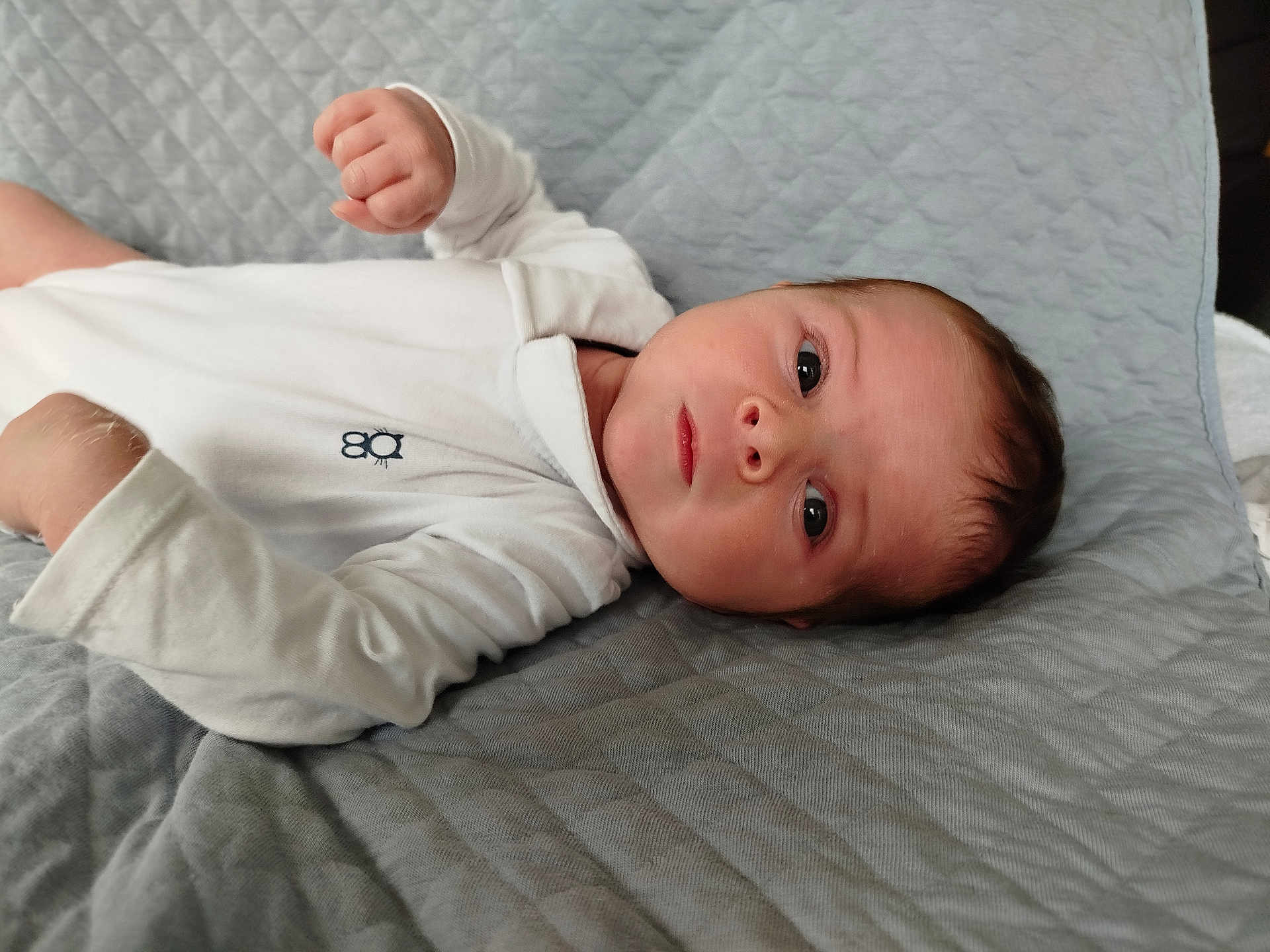 Gabin participe au concours pour gagner de l'argent avec cette photo : baby, infant, face, eyes, hand, onesie, white_clothing, blanket, quilted, soft_texture, lying_down, portrait, young_child, skin, head, curious, indoors, person, newborn, sleepwear