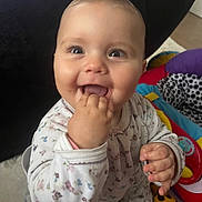 Alma a rejoint le concours — aidez-le/la à gagner de superbes lots ! baby, child, smiling, happy, indoor, toys, floral_onesie, cute, infant, face, hand, playful, bright_eyes, home, colorful, person, young_child, sitting, closeup, cheerful