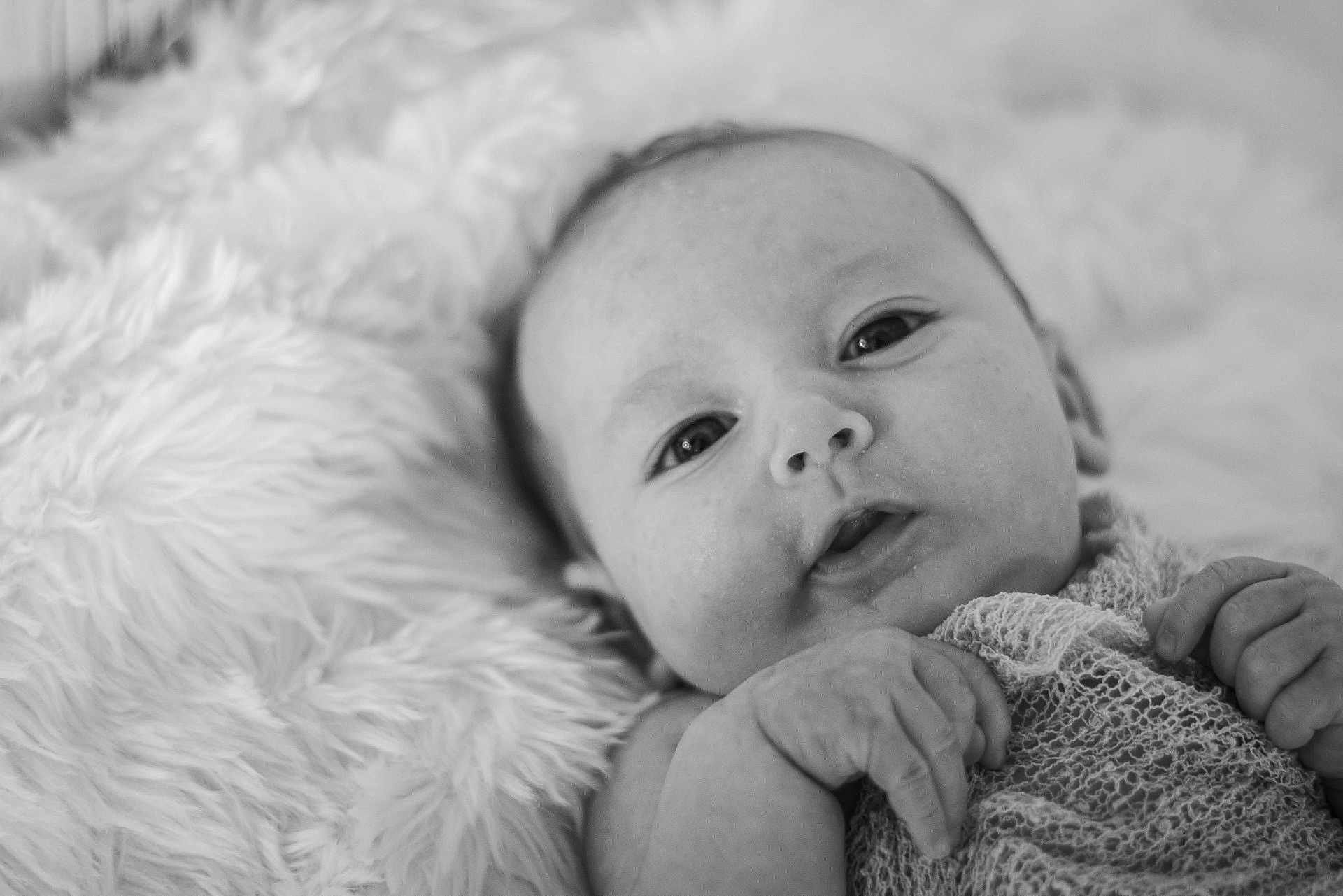 Sabrina is registered to the contest to win money with this photo: baby, infant, black_and_white, close_up, face, hands, blanket, texture, soft, cute, newborn, portrait, lying_down, expression, skin, eyes, hand, knitted_fabric, cozy, calm