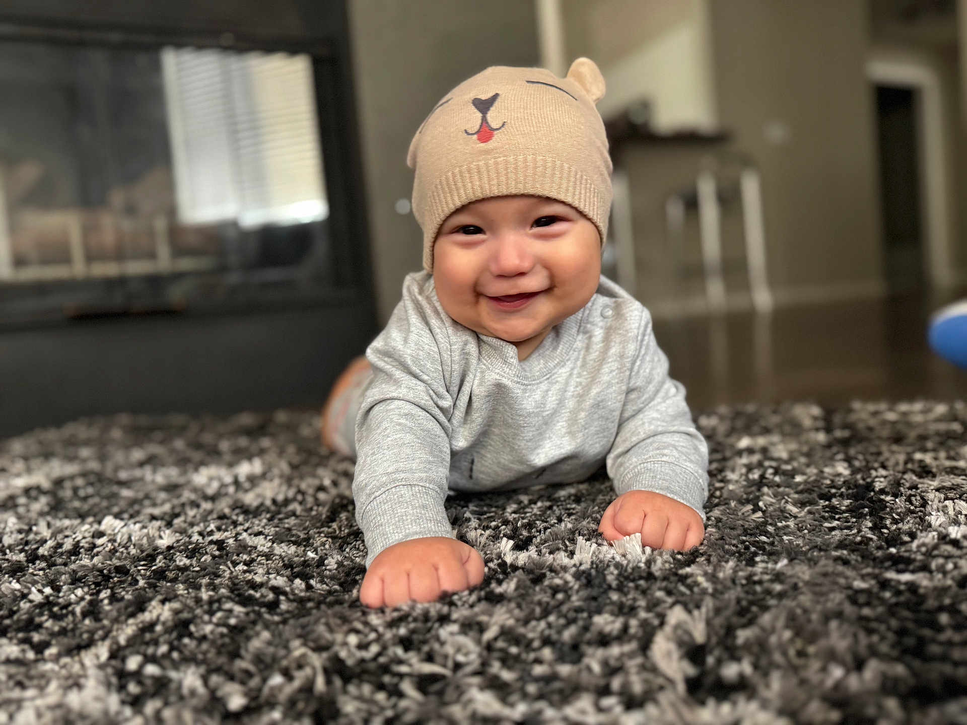 Juan is registered to the contest to win money with this photo: baby, child, smiling, beanie, hat, indoor, carpet, floor, cute, happy, infant, person, clothing, portrait, headwear, toddler, home, cozy, furniture, expression