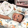 baby, smiling, infant, blanket, cushion, elephant_pattern, rainbow_pattern, baby_bed, pink, white, soft_toys, indoor, happy, face, child, resting, cozy, cute, person, nursery