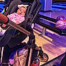 Serena is registered to the contest to win money with this photo: baby, stroller, bowling_alley, bowling_balls, bowling_shoes, child, pink_clothing, headband, flooring, bag, person, indoor, lane, seating, recreation, sports, leisure, colorful, curious, casual