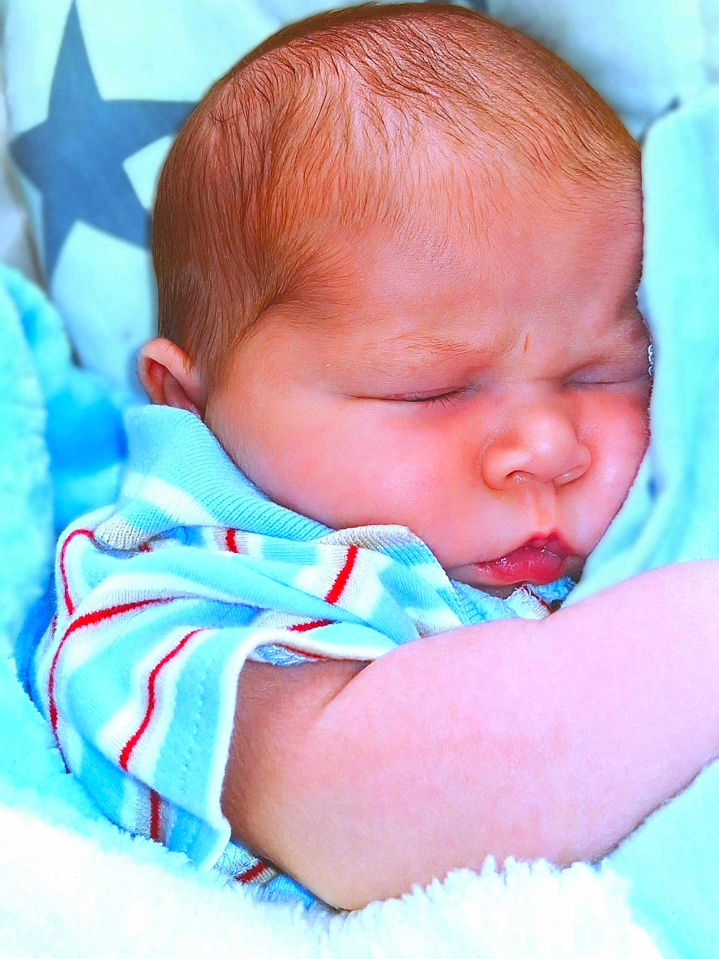 Winston is registered to the contest to win money with this photo: baby, sleeping, infant, blue_blanket, star_pattern, striped_clothing, closeup, peaceful, soft_texture, newborn, cute, face, arm, skin, portrait, cozy, child, resting, indoors, warm