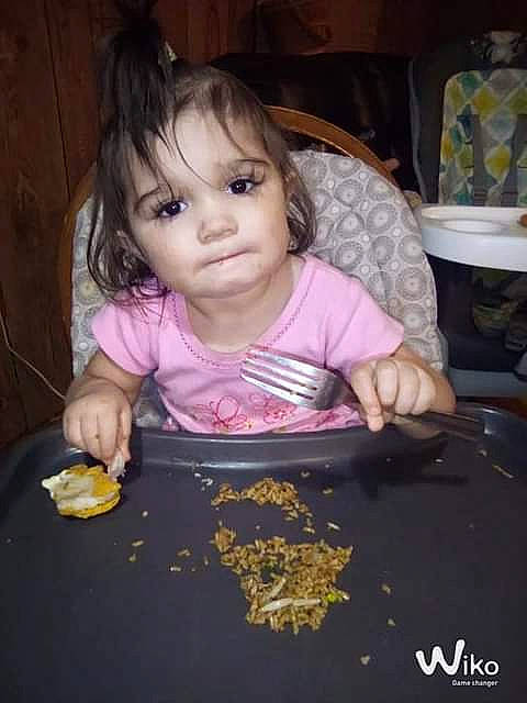 Grace is registered to the contest to win money with this photo: baby, chair, cheek, child, chin, comfort_food, cuisine, dish, eating, fun, hand, iris, meal, nose, person, play, room, sitting, sweetness, tableware