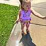 barbie, child, curly_hair, daylight, expression, footwear, gesture, grass, hair, outdoor, playful, sandals, shadow, sidewalk, summer, sunlight, swimsuit, toddler, water, wet_surface