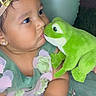 adorable, baby, child, closeup, crown, curious, cute, dress, earrings, face, flower, frog, green_dress, hands, indoors, plush_toy, portrait, soft_toy, toddler, toy