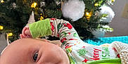 Kingston is registered to the contest to win money with this photo: baby, infant, christmas_tree, holiday, pajamas, blanket, face, smile, indoors, decorations, lights, festive, cozy, child, portrait, christmas, warm, happy, cute, celebration