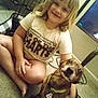 child, dog, carpet, tshirt, indoor, pet, smiling, sitting, floor, television, cage, collar, tag, short_hair, barefoot, cord, furniture, happy, home, animal