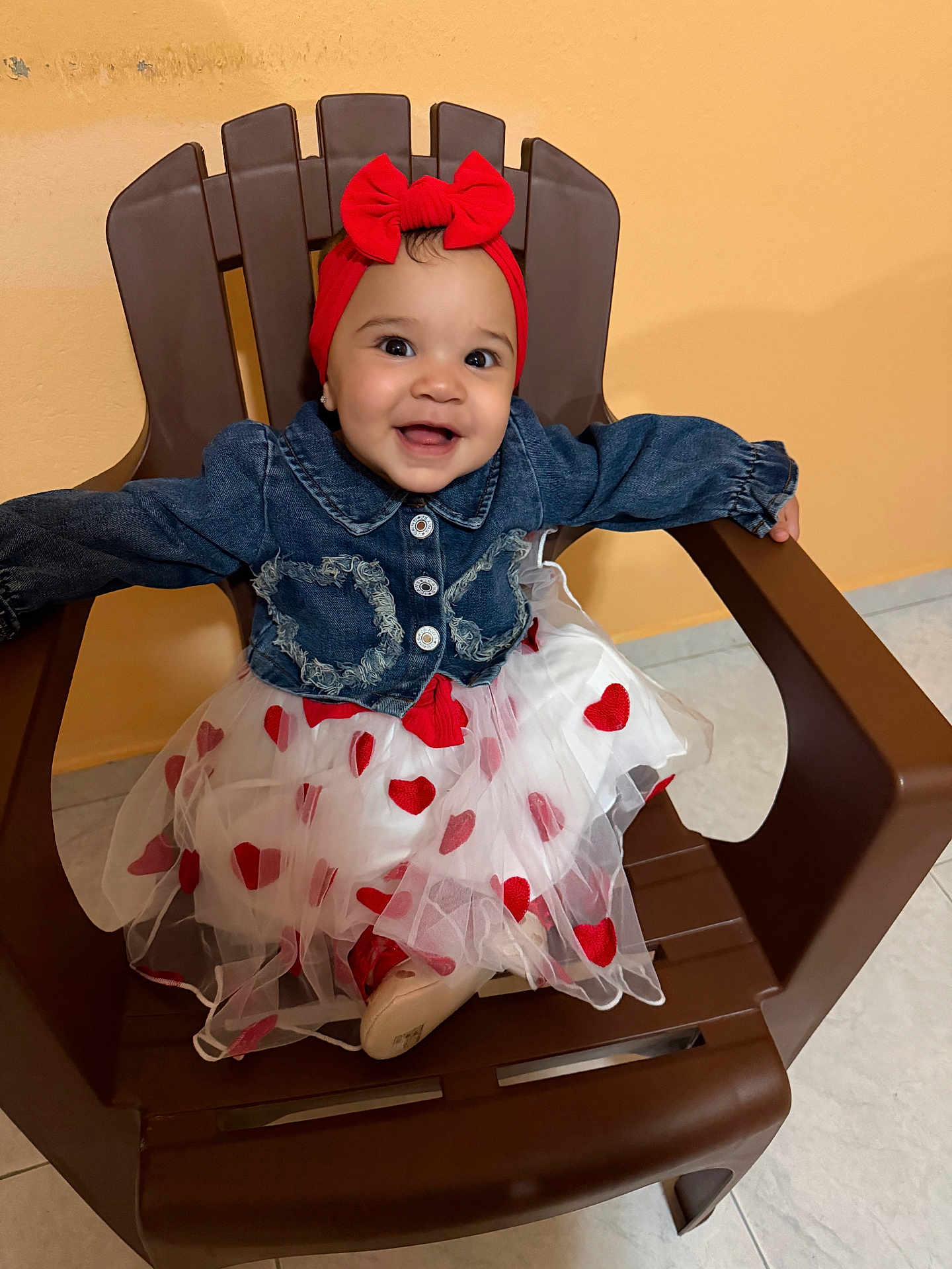 Emily joined the competition — help win amazing prizes! accessory, baby, bow, child, cute, denim_jacket, fashion, happy, hearts, indoor, orange_wall, plastic_chair, portrait, red_headband, shoe, sitting, smile, tile_floor, toddler, tulle_skirt