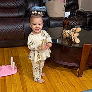 Emily joined the competition — help win amazing prizes! toddler, child, smiling, standing, portrait, indoors, living_room, sofa, coffee_table, stuffed_animal, leopard_toy, basket, cat_design, hardwood_floor, pajamas, patterned_clothing, hair_bows, happy, home_interior, photography