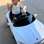 Emily joined the competition — help win amazing prizes! toddler, child, toy_car, sunglasses, white_tank_top, shorts, sidewalk, outdoor, sunlight, small_bottle, miniature_vehicle, summer, cute, fashion, playtime, casual_clothing, happy, young_child, driving, fun