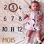 baby, infant, child, dress, pink, polka_dot, blanket, numbers, wooden_ring, stars, rainbow, socks, lying_down, cute, playful, age_marker, months, white_background, decor, portrait