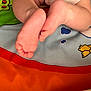 baby, feet, toes, skin, play_mat, cartoon, bird, tree, colorful, child, infant, closeup, soft, cute, small, leg, resting, pattern, fabric, indoors
