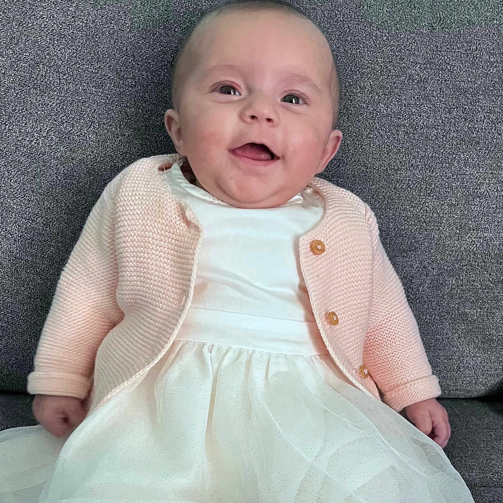 Romy a rejoint le concours — aidez-le/la à gagner de superbes lots ! baby, smiling, child, dress, cardigan, pink, white, sitting, portrait, happy, indoor, cute, face, person, young, infant, clothing, fabric, texture, background