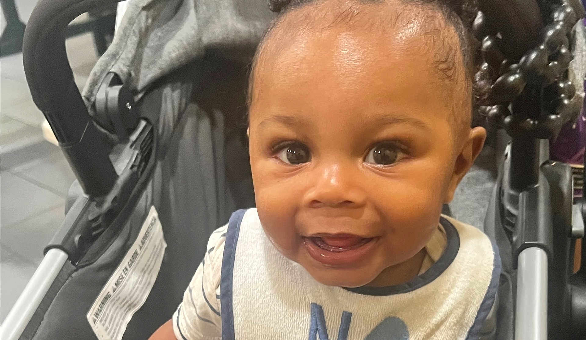 Omri joined the competition — help win amazing prizes! baby, child, smiling, face, stroller, bib, clothing, indoor, cute, young, portrait, infant, person, happy, eyes, tongue, seat, closeup, skin, head